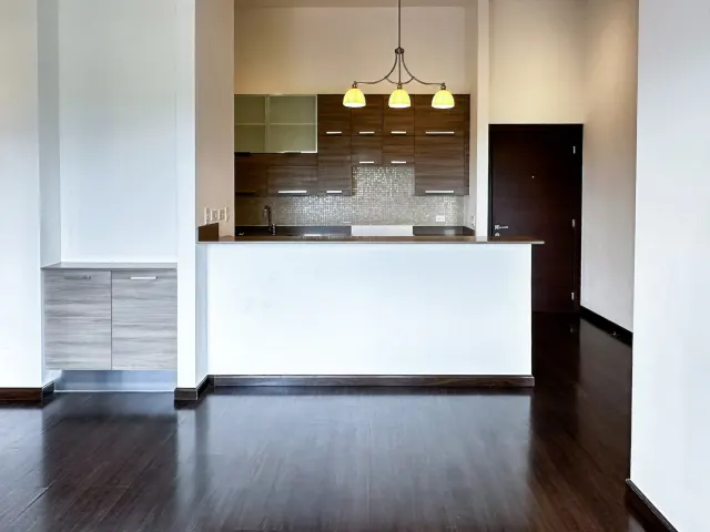 Interior view of a kitchen featuring dark wood cabinetry, a breakfast bar with a white base, and a three-light pendant fixture above.