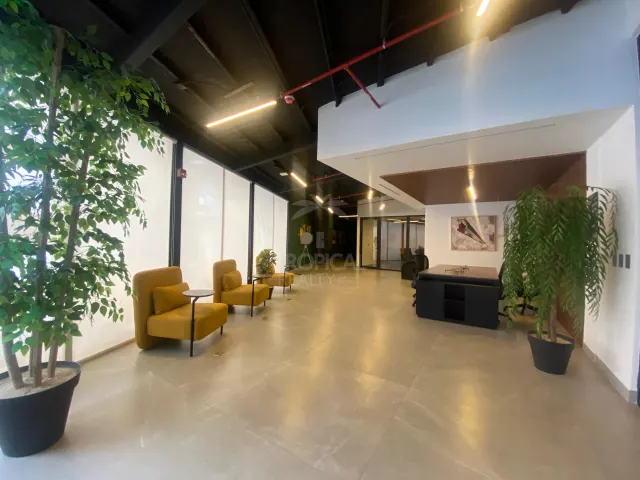 Reception area featuring yellow armchairs with small side tables along a large glass wall, and a dark desk near the back.
