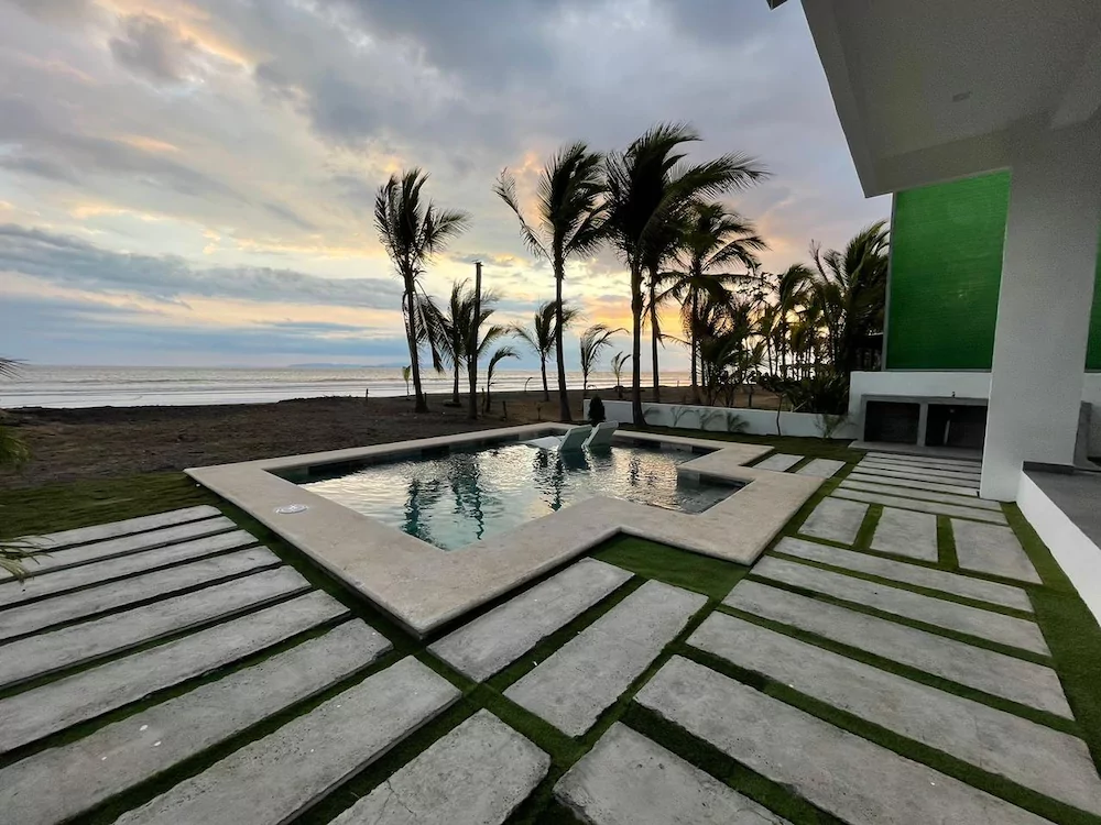 Pool and palms at a Tivives beach house as the sun sets over the Pacific