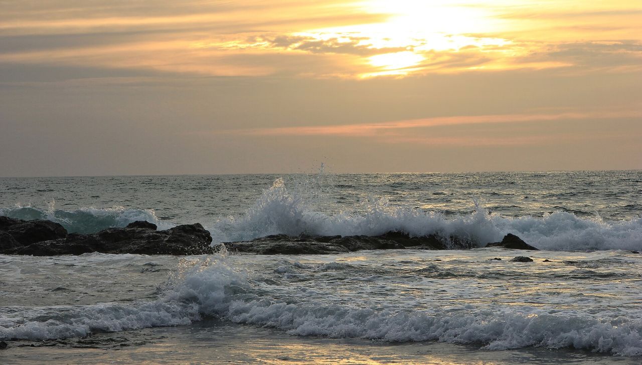 Surf breaking over rocks as the sun goes down over the Pacific